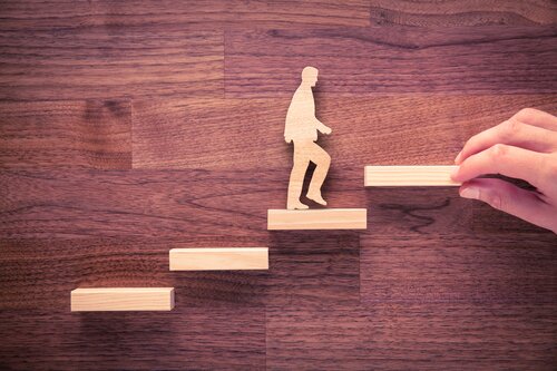 Male wooden figure walking up steps. (iStock.com/Jirsak)
